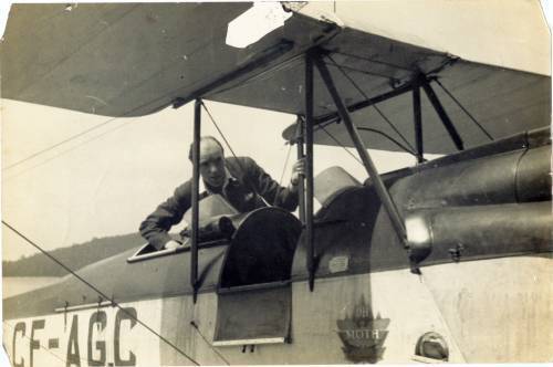 A DeHaviland Gypsy Moth biplane about 1929 at Camp Limberlost, near Petersburg Ontario. Royal Canadain Air Force Reserve Major Wrathall is helping someone get strapped into the rear cockpit.
